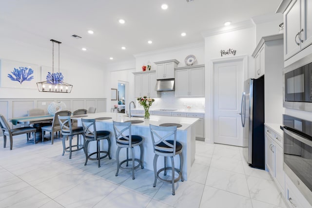 kitchen with appliances with stainless steel finishes, gray cabinets, a kitchen breakfast bar, and pendant lighting