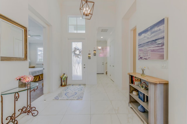 foyer featuring ceiling fan with notable chandelier