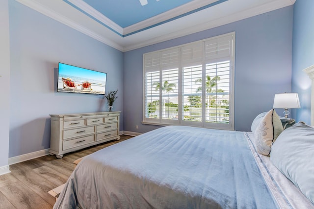 bedroom with a raised ceiling, crown molding, light hardwood / wood-style flooring, and ceiling fan