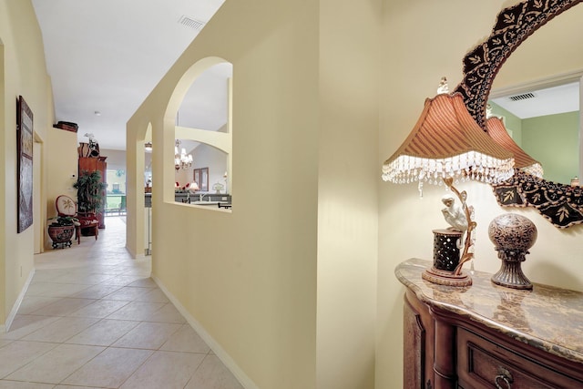 hallway featuring light tile patterned flooring and an inviting chandelier