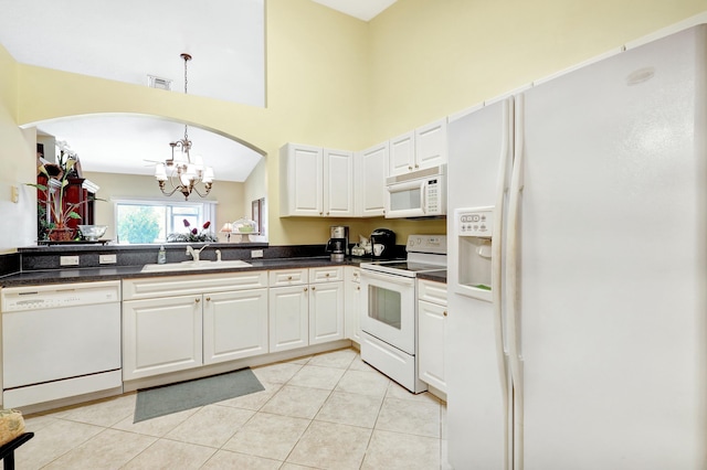 kitchen with white appliances, a chandelier, light tile patterned floors, sink, and white cabinetry