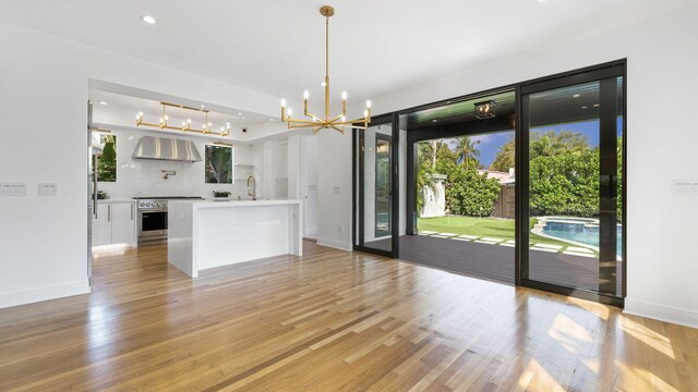 kitchen featuring white cabinetry, stainless steel built in fridge, hanging light fixtures, and plenty of natural light