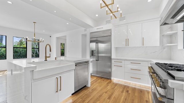 kitchen featuring pendant lighting, white cabinetry, sink, a chandelier, and premium appliances