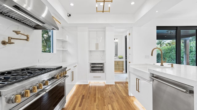 kitchen featuring sink, stainless steel appliances, light hardwood / wood-style floors, white cabinets, and island exhaust hood