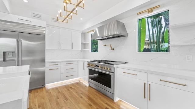 kitchen with white cabinetry, a wealth of natural light, premium appliances, and wall chimney range hood