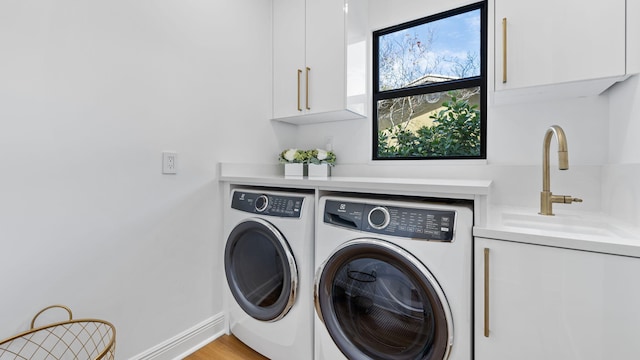 laundry area with sink, washing machine and dryer, cabinets, and light wood-type flooring