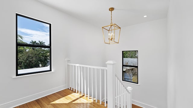 stairway with wood-type flooring and a chandelier