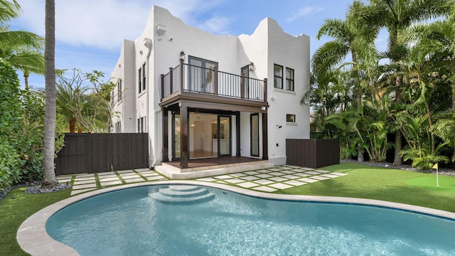 back of property with a fenced in pool, a balcony, and a patio area