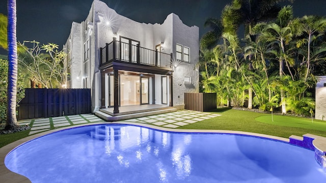 rear view of house featuring a balcony, a fenced in pool, and a patio