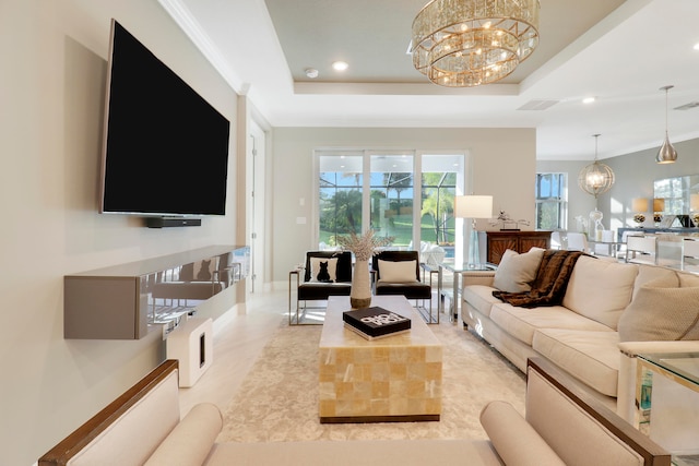 living room featuring a tray ceiling, crown molding, and a chandelier