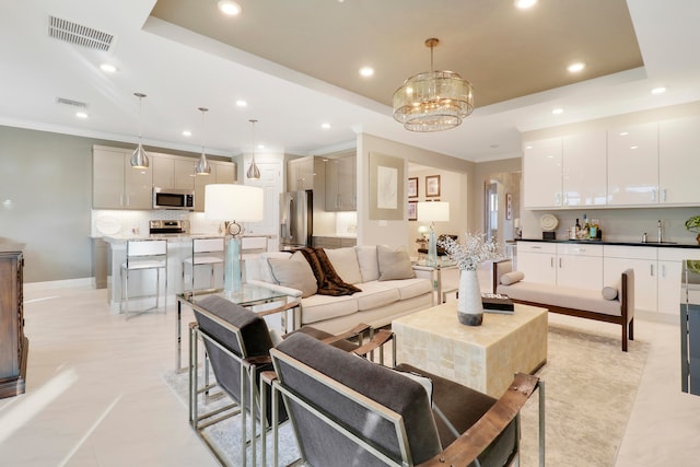 tiled living room featuring a notable chandelier, a raised ceiling, and sink