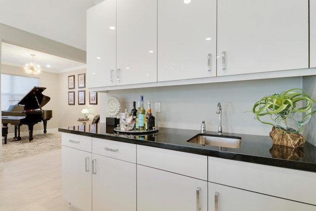 bar featuring white cabinetry, sink, an inviting chandelier, crown molding, and light tile patterned flooring