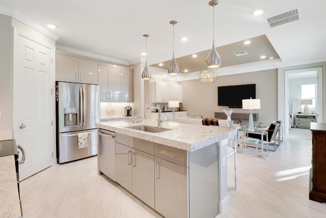 kitchen featuring pendant lighting, a center island with sink, sink, decorative backsplash, and stainless steel appliances