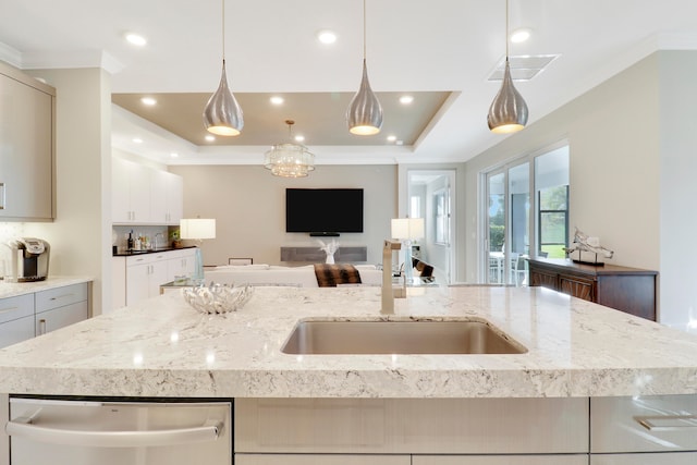 kitchen with a large island, dishwasher, hanging light fixtures, a raised ceiling, and light stone counters