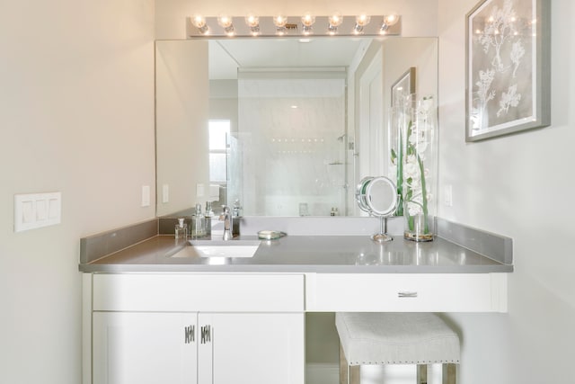 bathroom featuring tiled shower and vanity