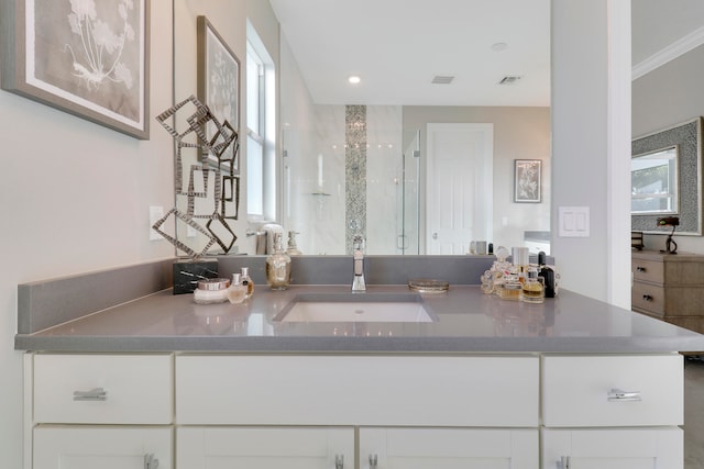 bathroom with vanity, a shower with shower door, and crown molding