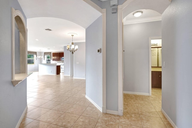 hall featuring light tile patterned floors and crown molding