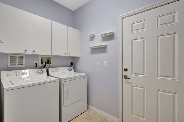 laundry room with cabinets, light tile patterned floors, and washer and dryer