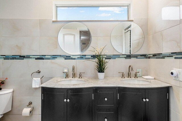 bathroom featuring a stall shower, vanity, toilet, and tile walls