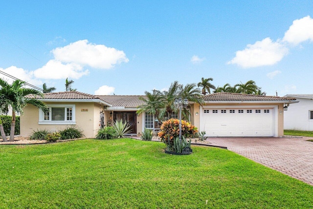 ranch-style house featuring an attached garage, a tiled roof, decorative driveway, stucco siding, and a front yard