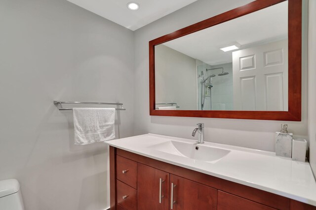 bathroom featuring vanity, toilet, and tiled shower