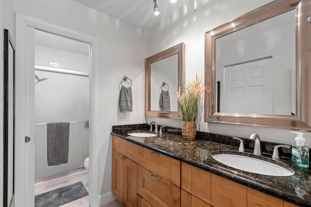 bathroom with tile patterned flooring, vanity, toilet, and a shower