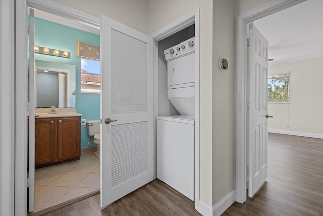 laundry room with sink, stacked washer / dryer, and light hardwood / wood-style flooring