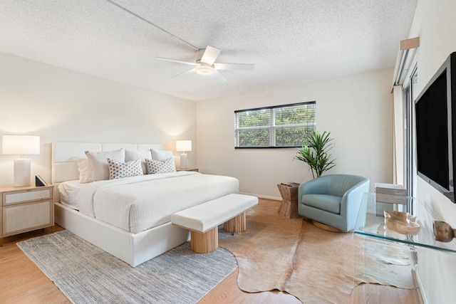 bedroom featuring ceiling fan, light hardwood / wood-style floors, and a textured ceiling