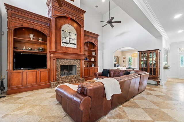 living room featuring crown molding, plenty of natural light, a high end fireplace, and high vaulted ceiling