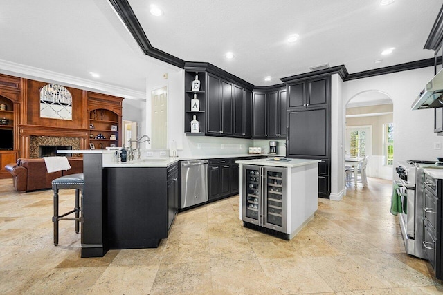 kitchen featuring ornamental molding, sink, wine cooler, appliances with stainless steel finishes, and a center island