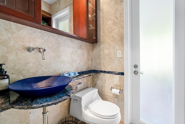 bathroom featuring sink, tile walls, and toilet