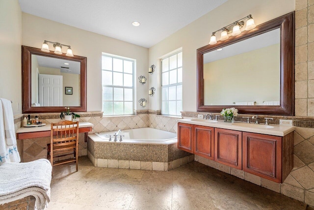 bathroom featuring vanity, tiled bath, and tile walls