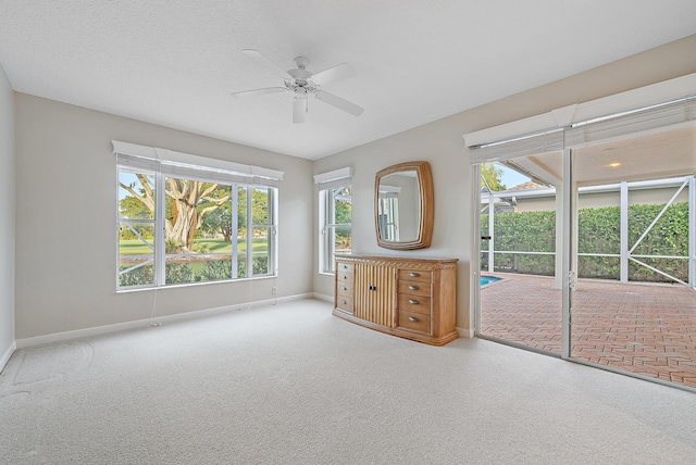 empty room featuring ceiling fan, carpet, a healthy amount of sunlight, and a textured ceiling