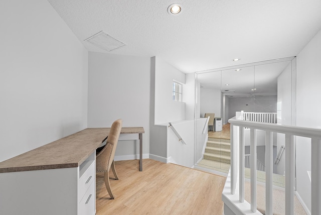 office with light wood-type flooring and a textured ceiling