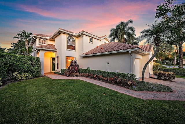 mediterranean / spanish-style house with a yard and a garage