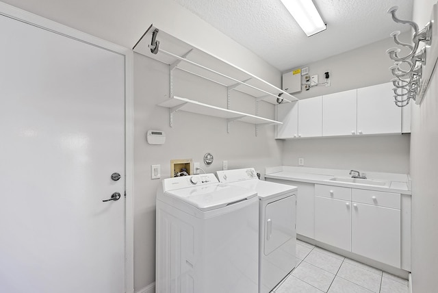 washroom with cabinets, a textured ceiling, sink, light tile patterned floors, and washing machine and dryer