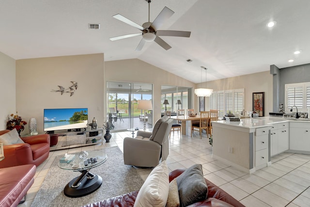 living room featuring ceiling fan with notable chandelier, lofted ceiling, and light tile patterned floors