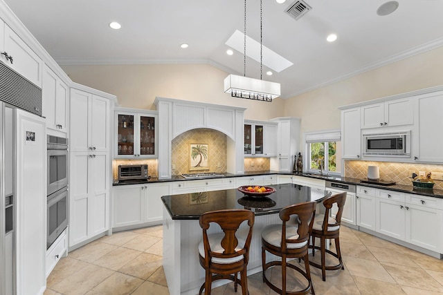 kitchen with tasteful backsplash, built in appliances, decorative light fixtures, vaulted ceiling with skylight, and a kitchen island