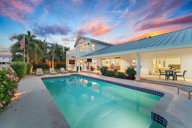 pool at dusk featuring a patio area