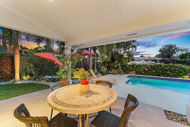 pool at dusk with a patio area