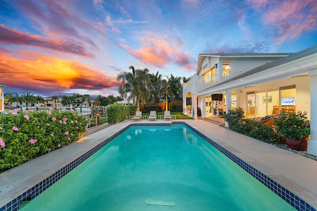 pool at dusk featuring a patio