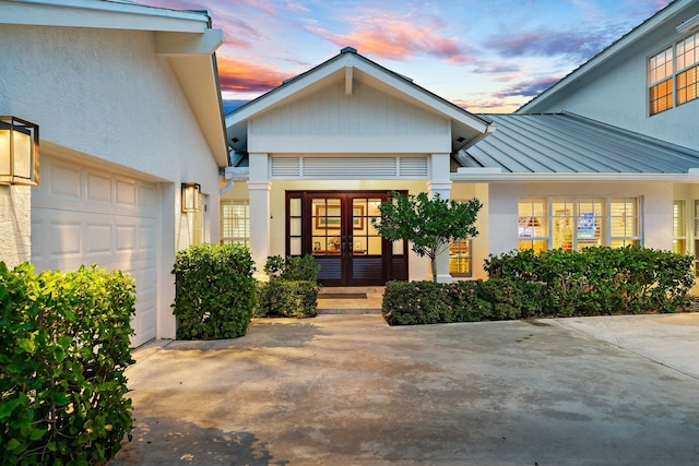 exterior entry at dusk featuring french doors and a garage