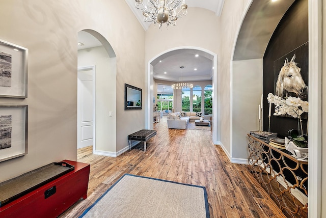 foyer featuring crown molding, wood-type flooring, and an inviting chandelier