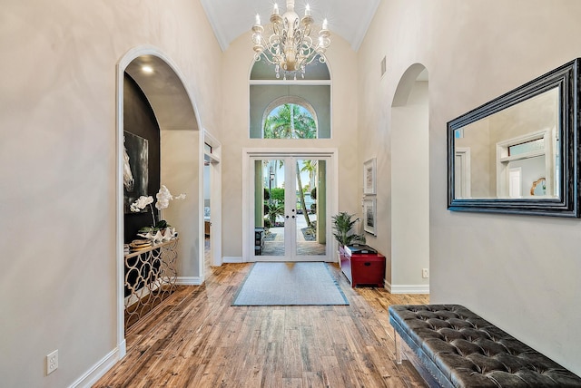 foyer entrance with crown molding, hardwood / wood-style floors, high vaulted ceiling, and an inviting chandelier