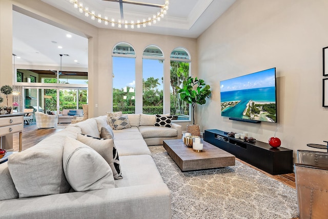 living room with light wood-type flooring, crown molding, and a notable chandelier