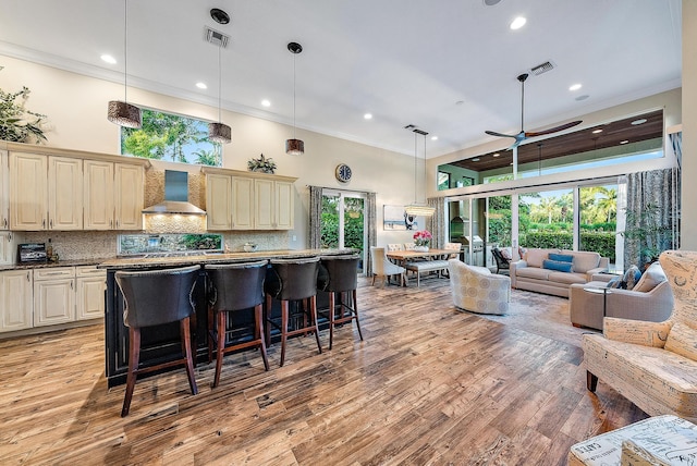 kitchen with pendant lighting, wall chimney exhaust hood, a healthy amount of sunlight, and light hardwood / wood-style flooring