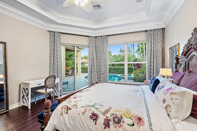 bedroom with ceiling fan, dark hardwood / wood-style floors, access to exterior, ornamental molding, and a tray ceiling