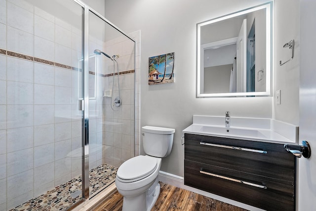 bathroom featuring vanity, toilet, wood-type flooring, and a shower with door