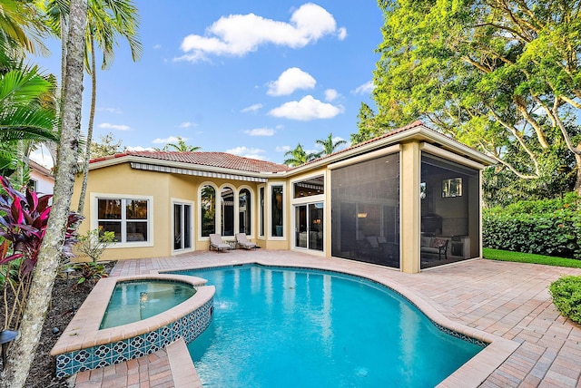 view of swimming pool featuring a sunroom, a patio area, and an in ground hot tub