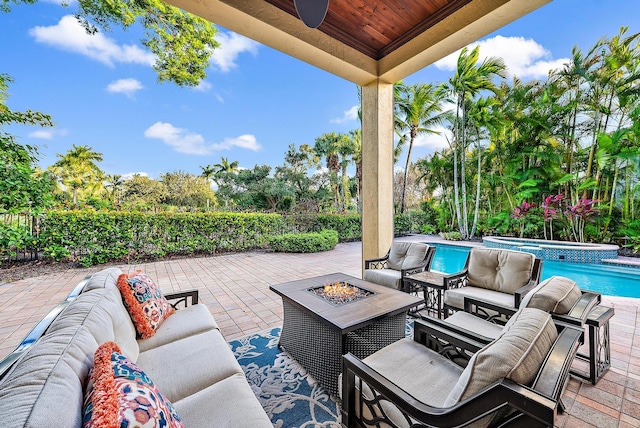 view of patio / terrace featuring ceiling fan, a swimming pool with hot tub, and an outdoor living space with a fire pit